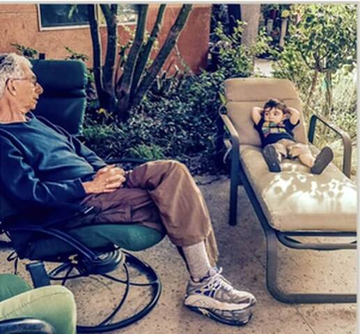 Young boy with grandfather talking while seated outdoors 